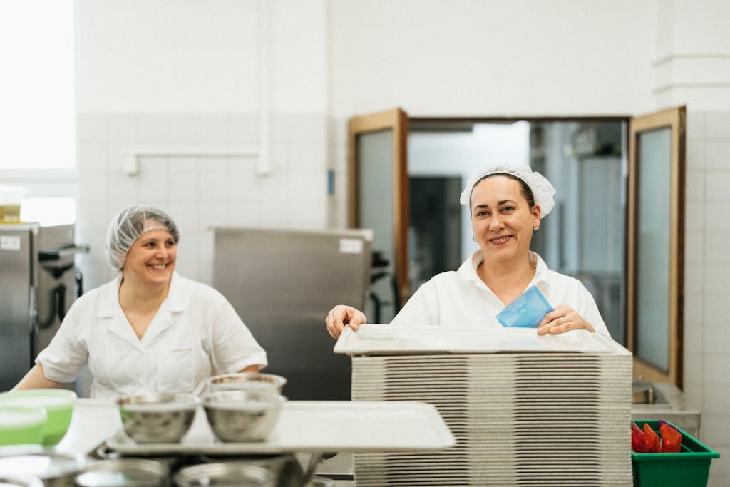Friendly cafeteria staff working together in a kitchen, showcasing teamwork and service.